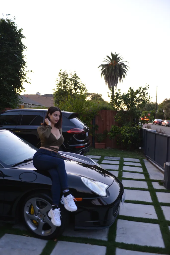 Julia Burch posing on a Porsche in Venice, California